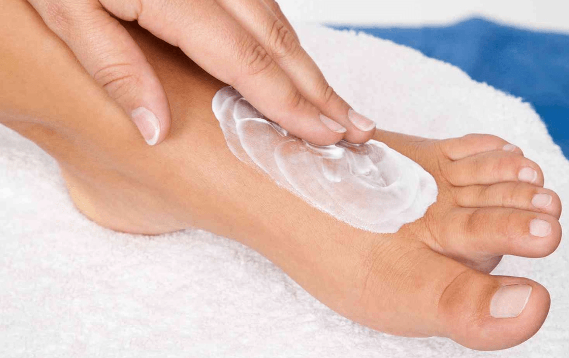 applying ointment against fungus on the feet